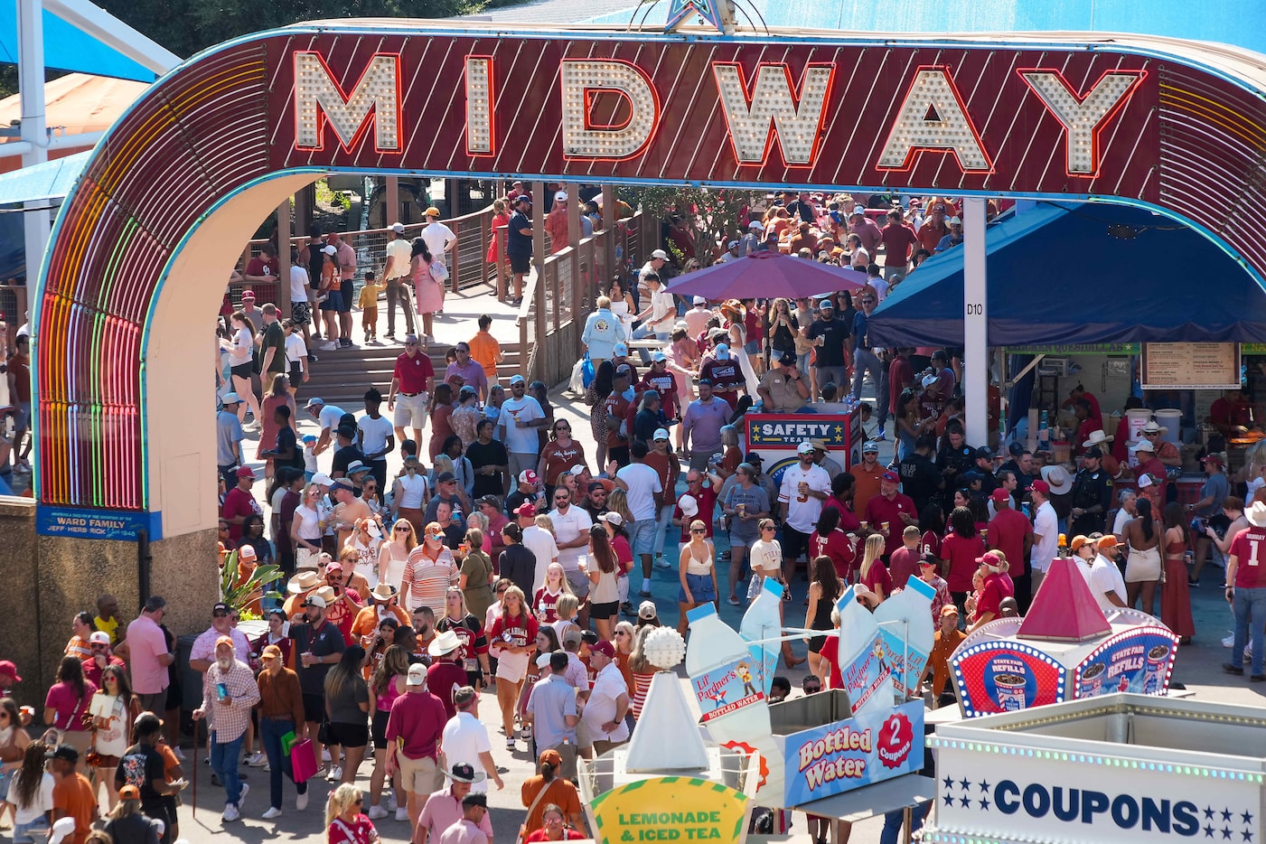 Fans walk the State Fair of Texas midway before an NCAA college football game between Texas...