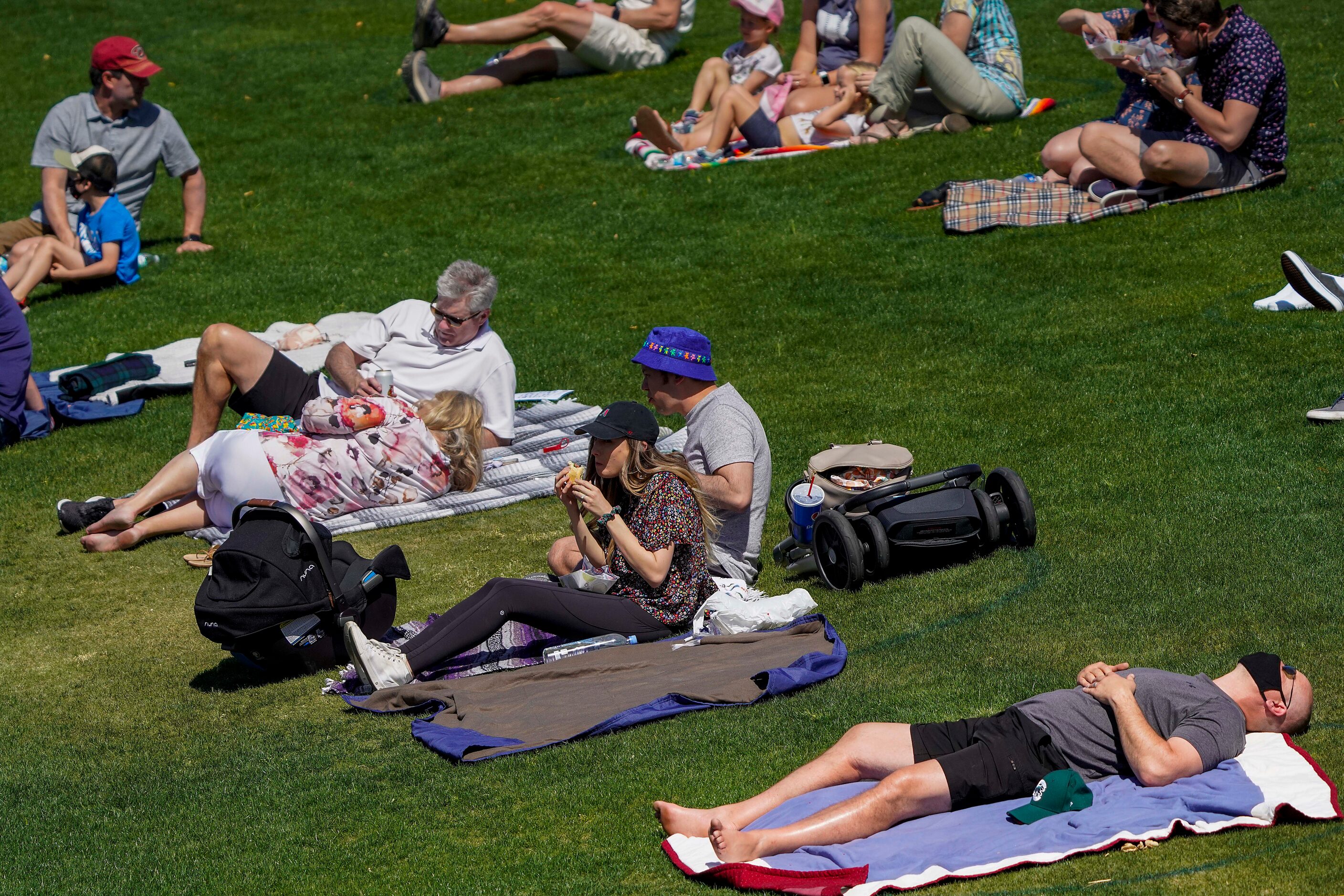 Fans relax in socially distanced pods on the outfield lawn during a spring training game...