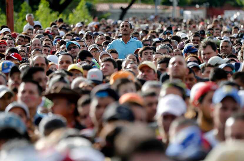 In this July, 2016 file photo, a man stands over the crowd waiting to cross the border into...