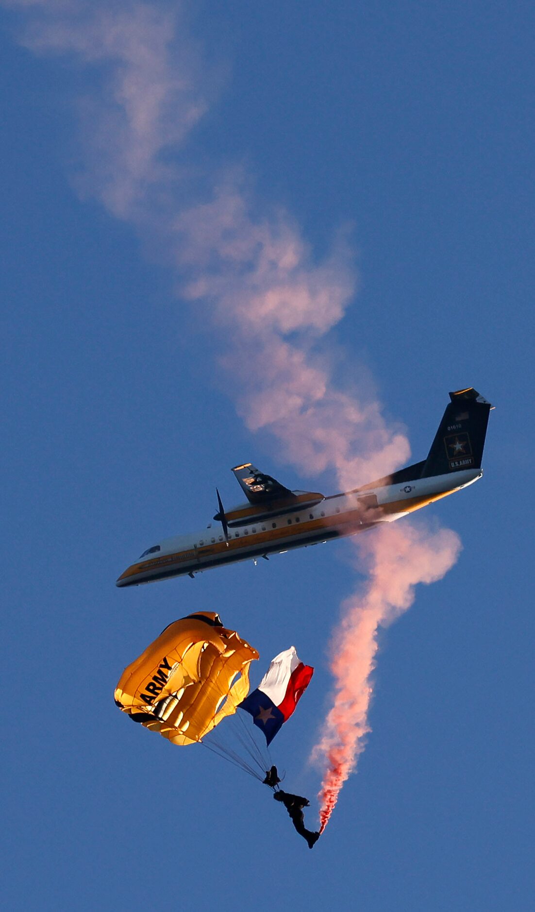 Members of the Army Golden Knights parachute team peform a jump with the Texas flag  before...