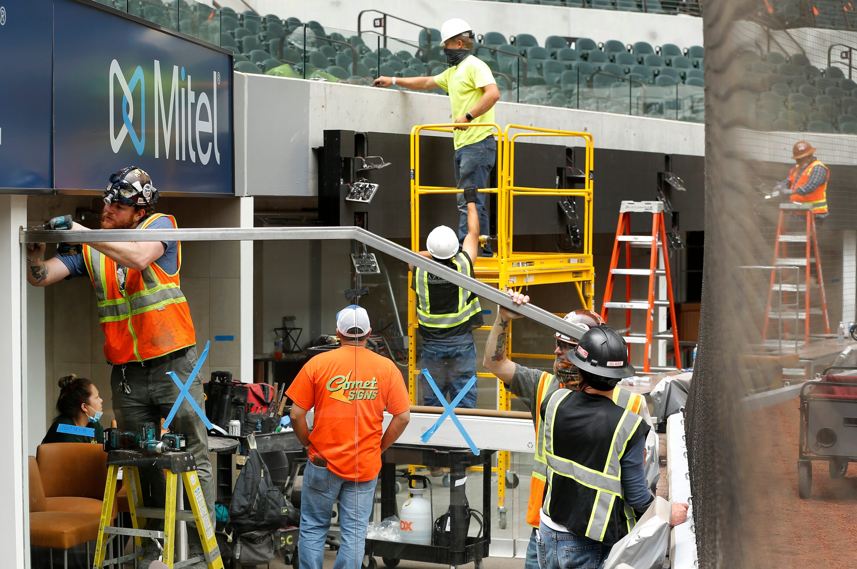 Construction workers finish out the field level suites behind home plate at the newly...