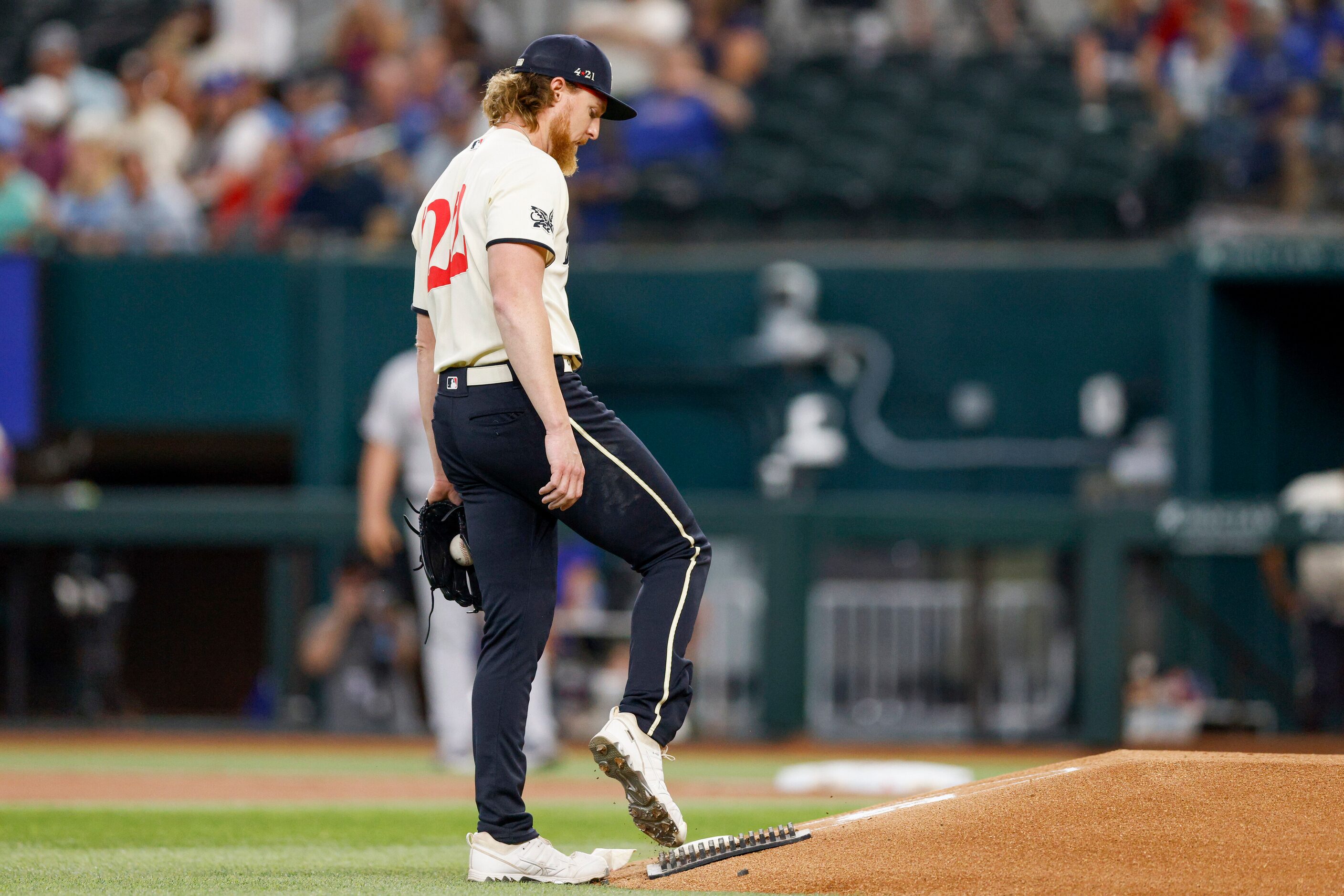 Texas Rangers starting pitcher Jon Gray (22) cleans his cleats after giving up a home run to...