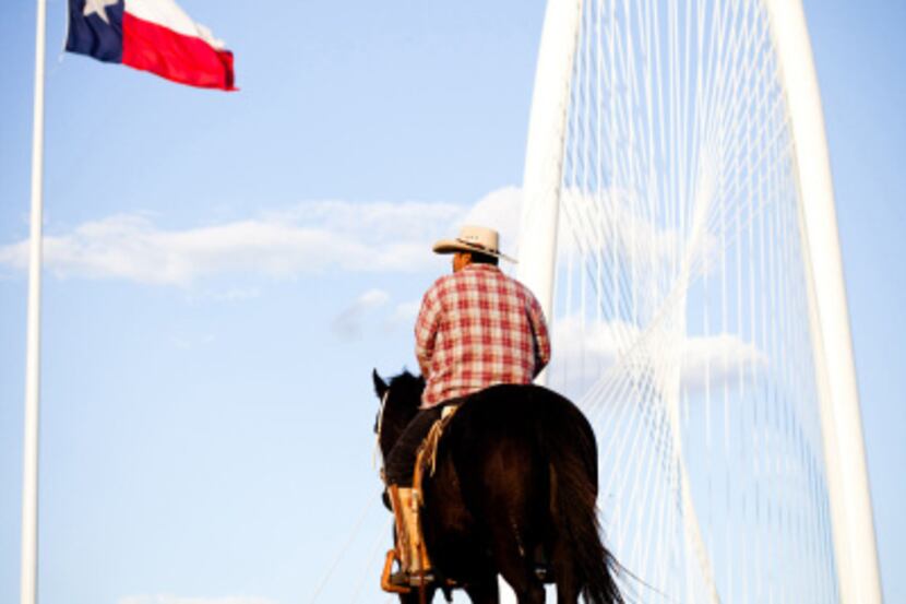 Reynaldo Guerra watches the Margaret Hunt Hill Bridge festivities from atop his horse while...