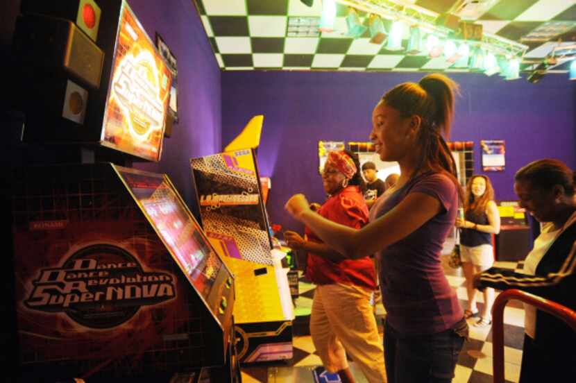 Doris Merchant (left) and her daughter Marlena Elliott, 15 play a dancing video game while...