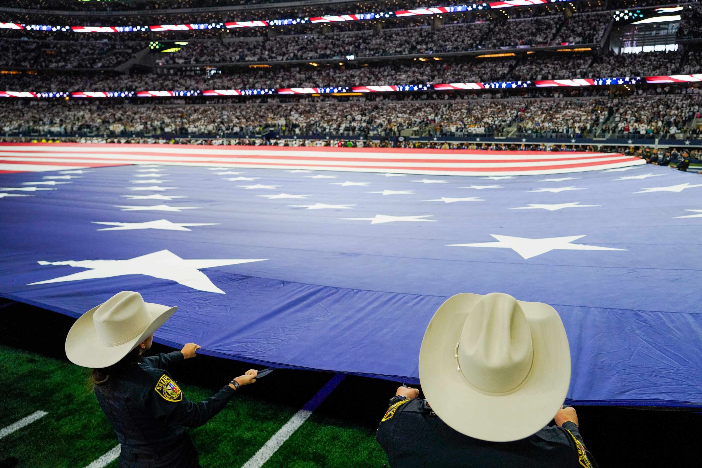 The American flag covers the field for the national anthem before an NFL wild-card playoff...