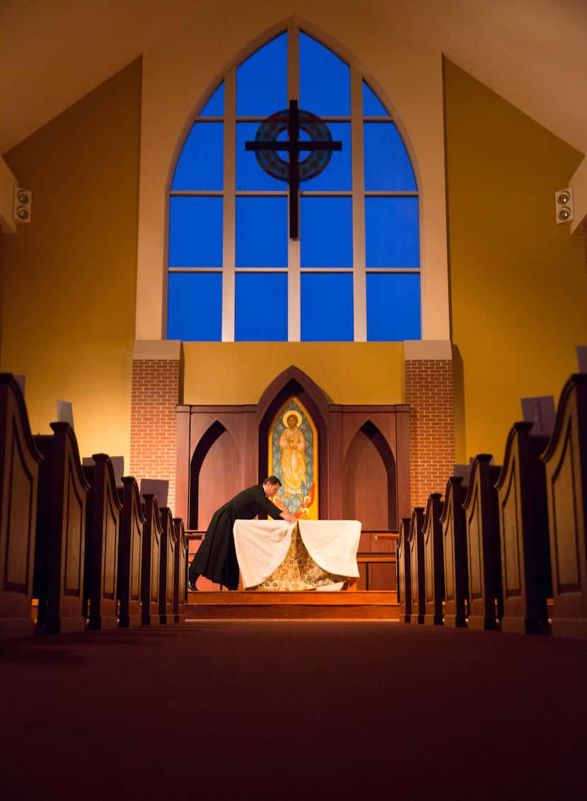 Following Holy Thursday service, Father Clayton Elder folds a cloth as he strips the alter...