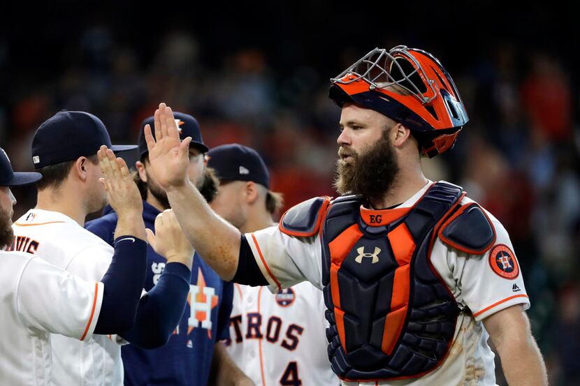 Houston Astros catcher Evan Gattis, right, celebrates with teammates after a baseball game...