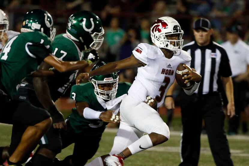 Mesquite Horn quarterback Jermaine Givens (right) gets out of the grasp of Arlington's Kyron...