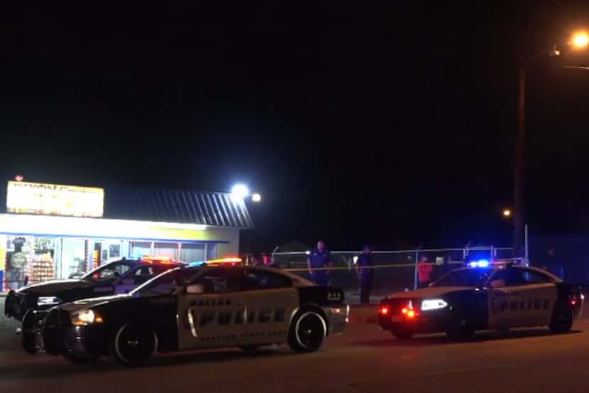 Dallas police squad cars gather outside a convenience store where a 20-year-old man was shot...