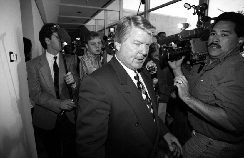 Jimmy Johnson fights his way back through a crowd of journalists to his office at Dallas...