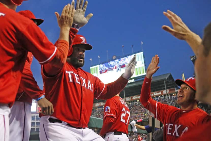 Texas first baseman Prince Fielder is greeted by teammates in the dugout after hitting a...