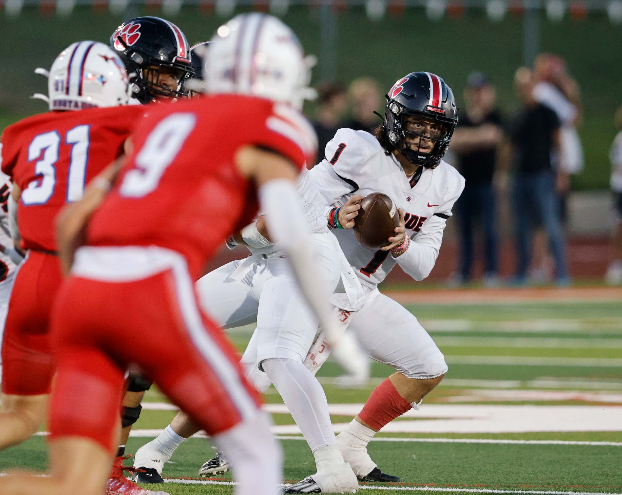 Colleyville Heritage's quarterback Luke Ullrich (1) looks to throw the ball under pressure...
