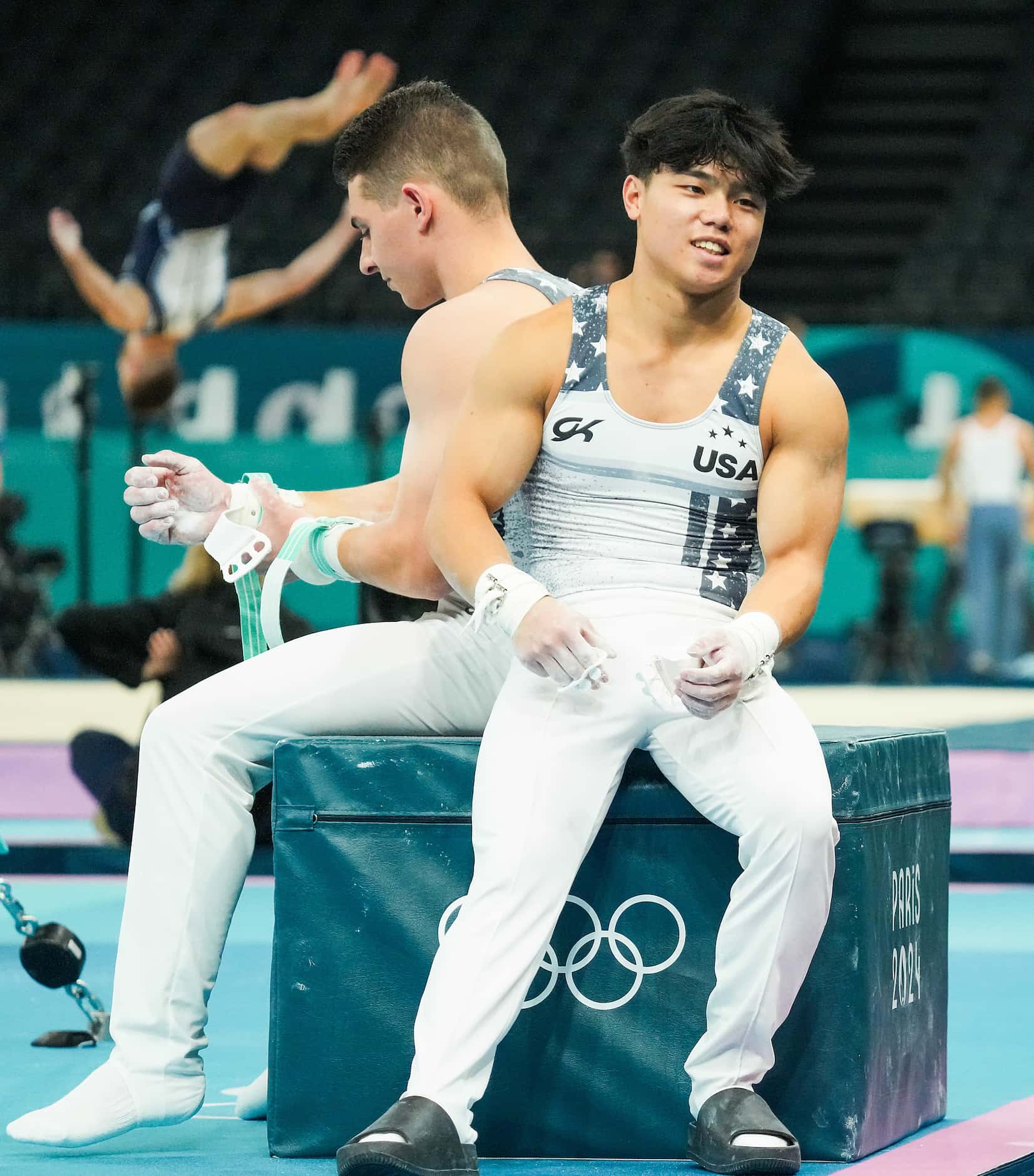 Asher Hong of the United States sits with Paul Juda  as they wait their turn on the high bar...