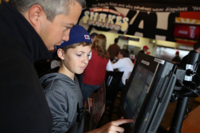 Steve Middleton  and his son, Ryan Middleton, 12, make selections on a point-of-sale...