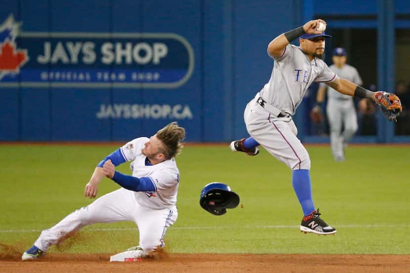 Toronto's Josh Donaldson, left, reacts after taking a knee to the head as Texas Rangers...