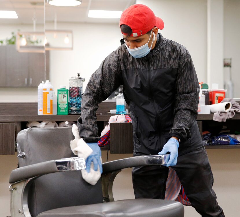 Carlos Lira cleans a chair between customers at Luciano's Barbershop in Dallas. Demand for...