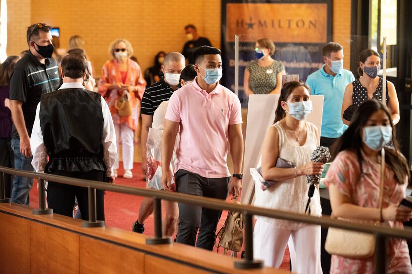 Vuong To (center), 21, wearing a face mask, walked into the Music Hall at Fair Park in...