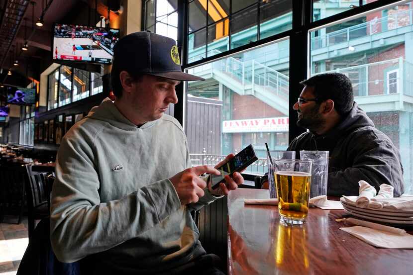 Taylor Foehl (left) of Boston, looked at the mobile betting app on his phone after placing a...
