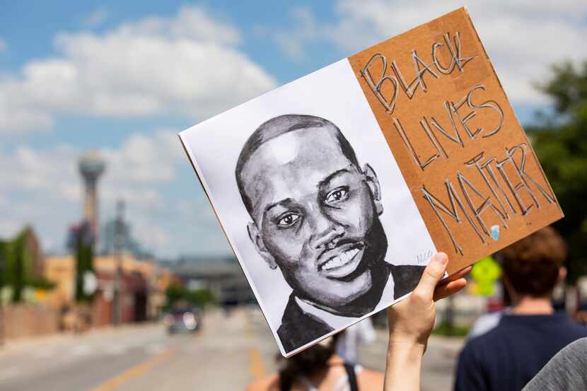 A protester in Dallas holds a sign depicting Ahmaud Arbery marches toward downtown during...