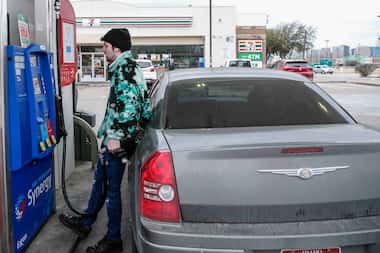 Hunter Crites watches the price tick up as he pumps gas at an Exxon gas station in Uptown on...