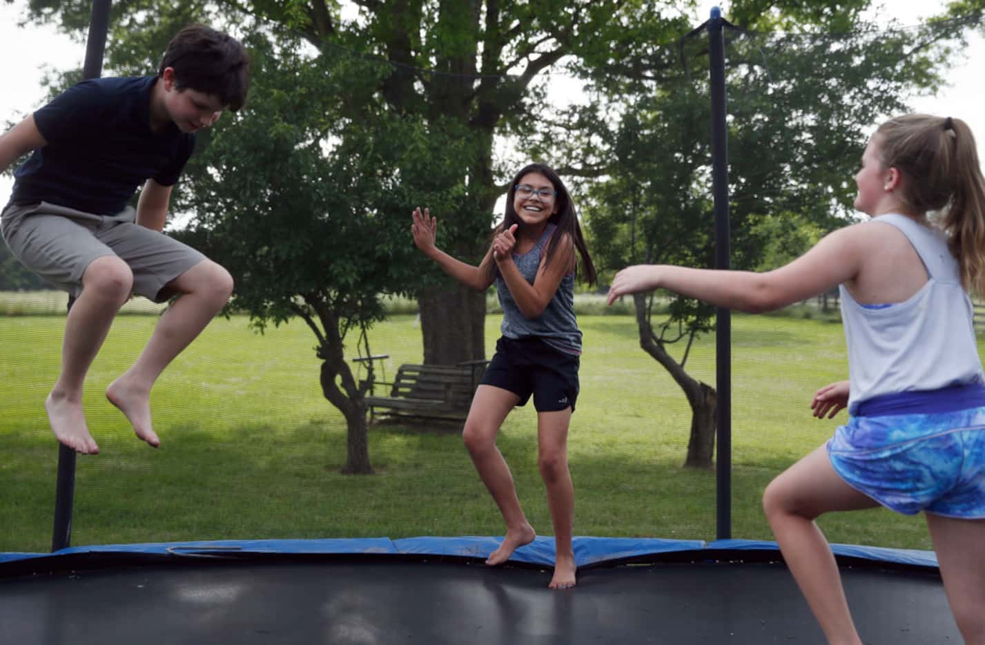 Emi plays on a trampoline at home with friends Simon Cooper (left) and Spencer Butrum...