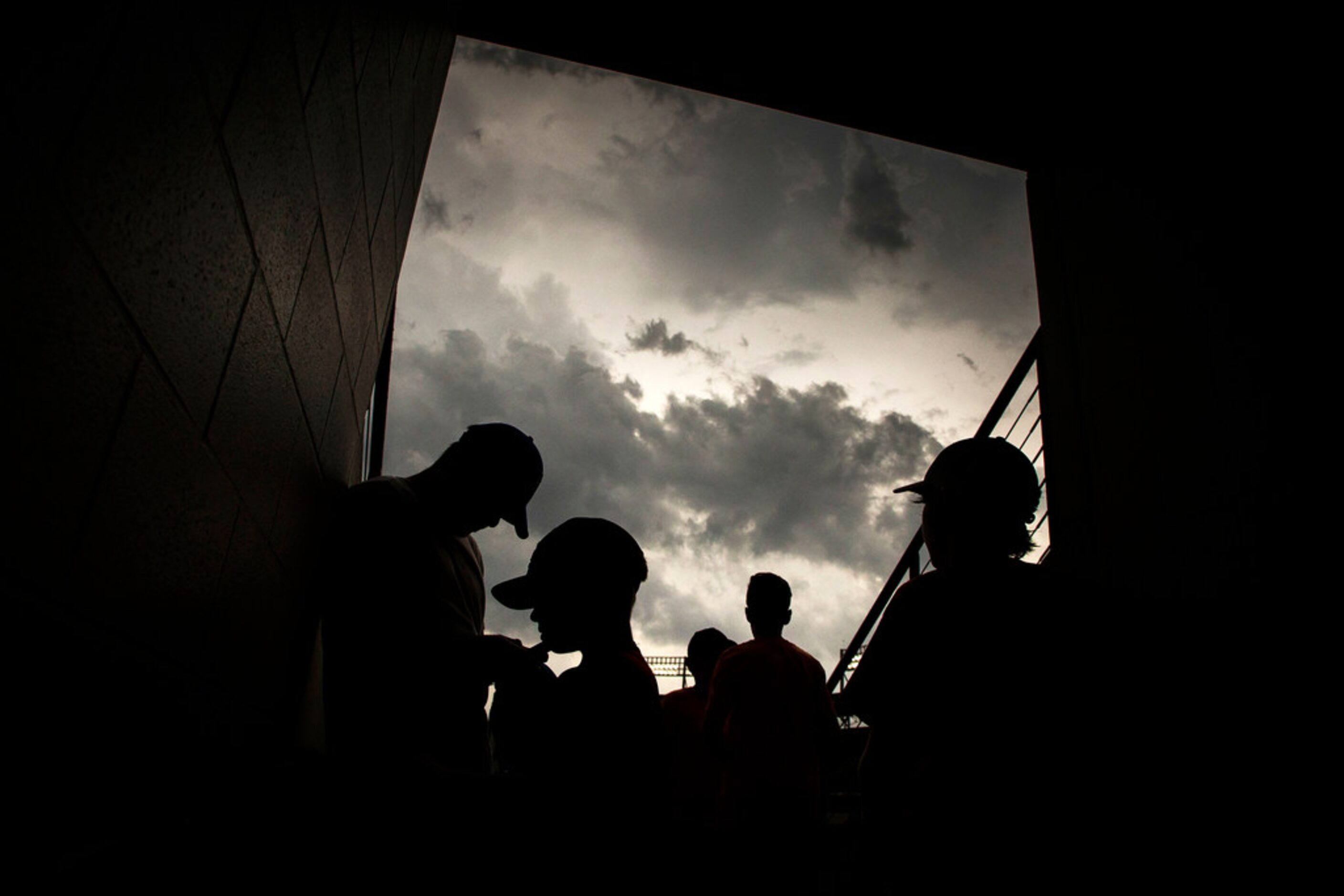 Fans take cover under threatening skies during a rain delay before a baseball game between...