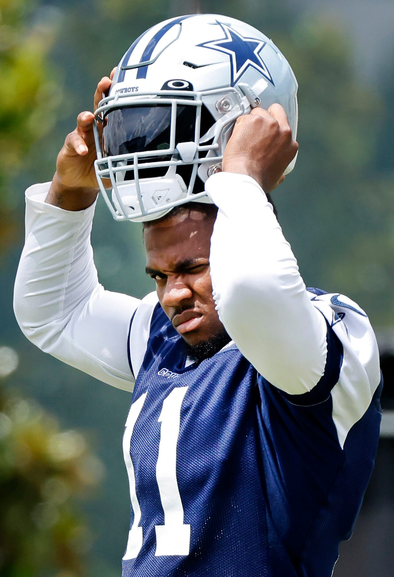 Dallas Cowboys linebacker Micah Parsons (11) draws down his helmet as training camp practice...