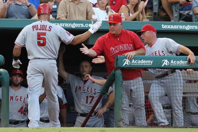 Albert Pujols is greeted at the dugout by manager Mike Scioscia after homering in the fourth...