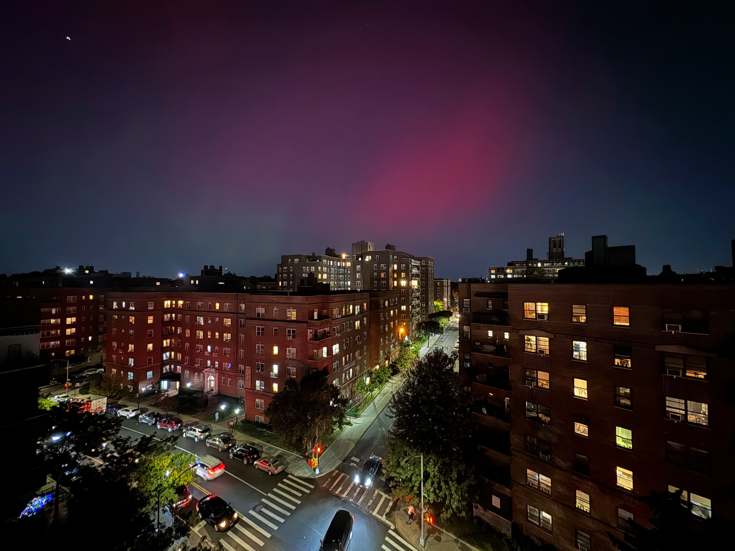 An aurora borealis glows in the night sky above apartment buildings in the Queens borough of...