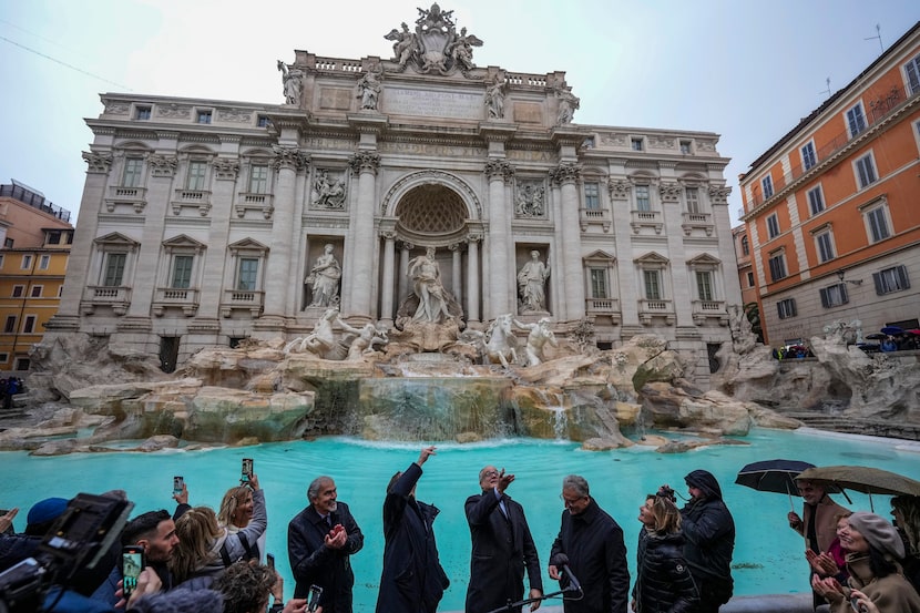 FILE - Rome's mayor Roberto Gualtieri, center, tosses a coin into the 18th century Trevi...