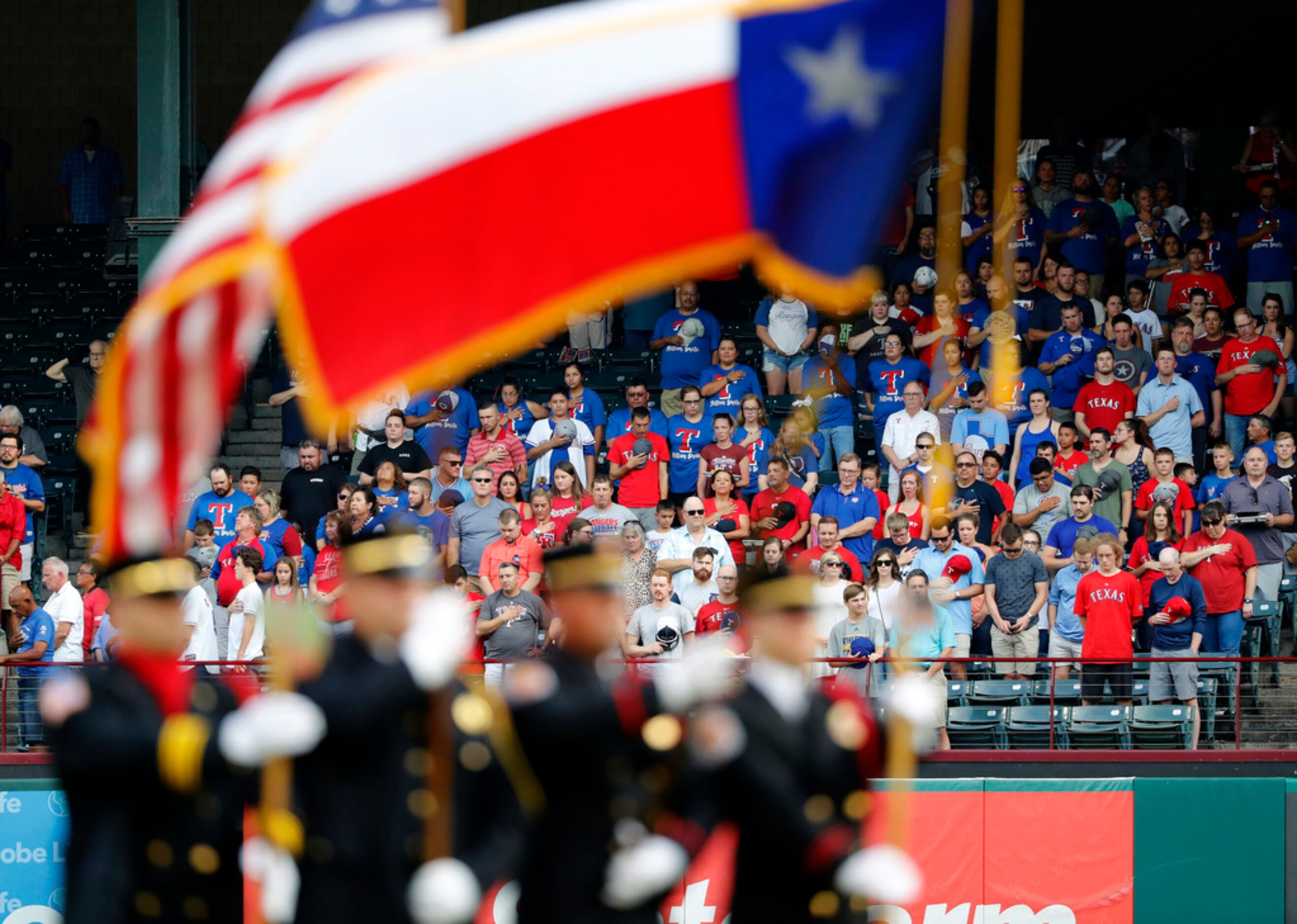 U.S. and Texas flags are held in the infield as fans and the teams observe a moment of...