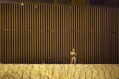 A guardsman patrols the 30 ft border wall where migrant people waited on the U.S. side of...