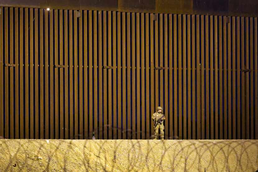 A guardsman patrols the 30 feet border wall where migrant people waited on the U.S. side of...