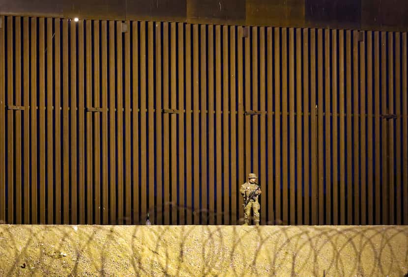 A guardsman patrols the 30-foot border wall where migrants waited on the U.S. side of the...