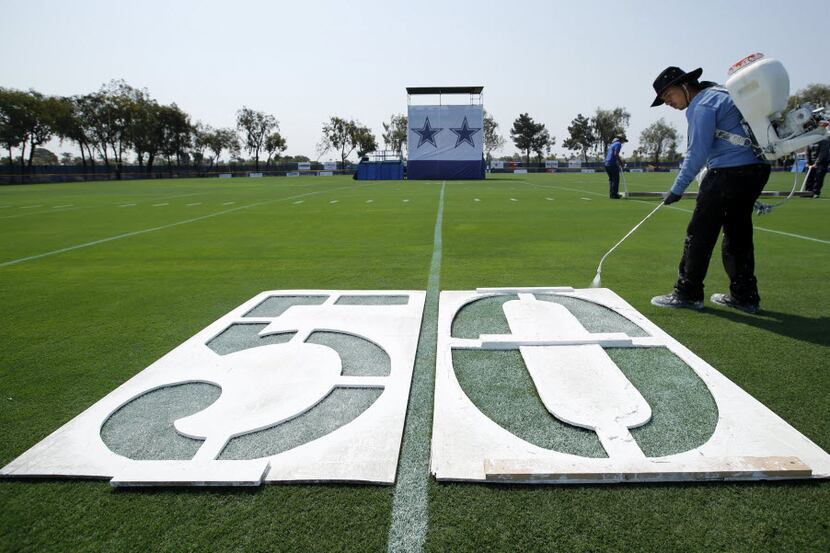 Robert Vega of Oxnard City Corps spray paints the 50 yard line markers on a practice field...