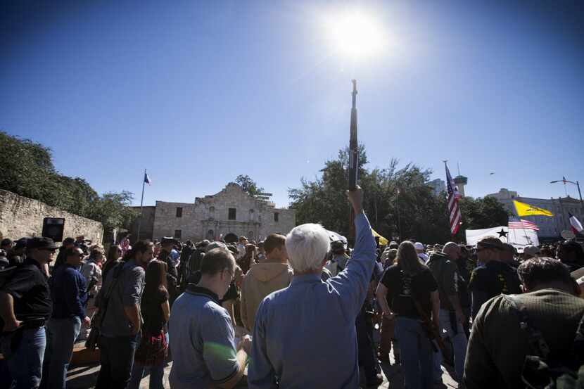 A demonstrator raises his rifle during a pro-gun rally at the Alamo in San Antonio, Oct. 19,...