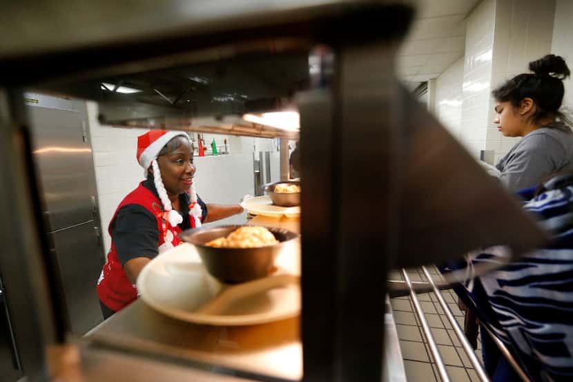 Line server Joyce Cummings (left) serves warm food to students at A. Maceo Smith New Tech...