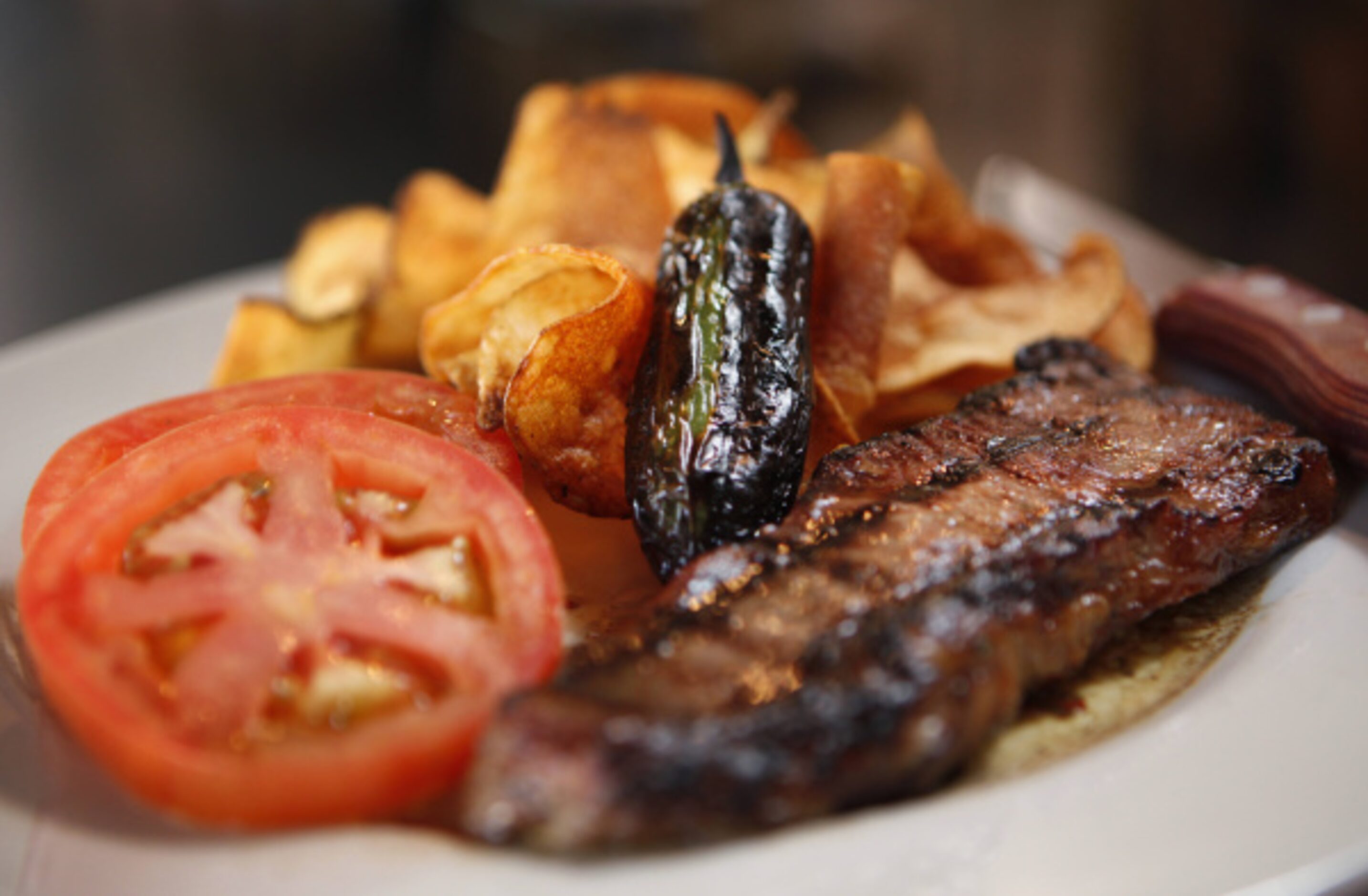 Steak frites, a strip steak topped with a savory herb-garlic compound butter, at AllGood...