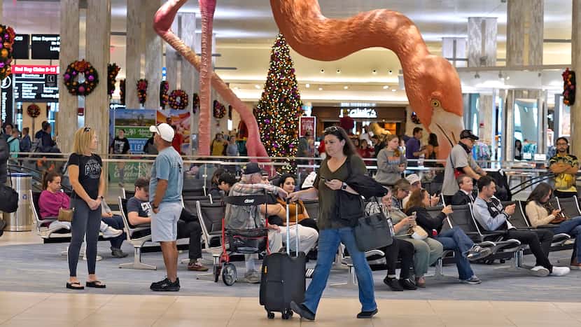 FILE - Holiday travelers pass by "Phoebe" the Flamingo at the Tampa International Airport,...