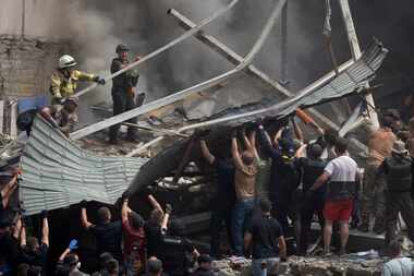 Rescuers and volunteers clean up the rubble and search victims after Russian missile hit the...