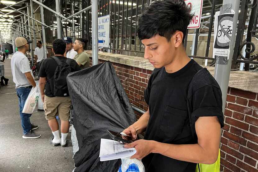 Dilan Jimenez goes through text messages as he stands outside a shelter, after arriving on a...
