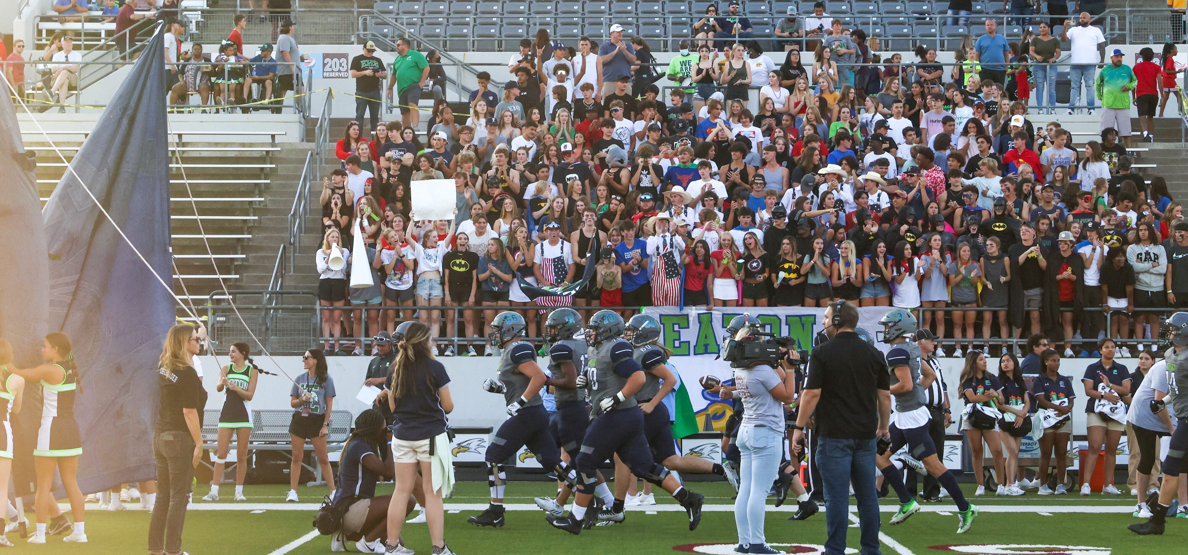 V.R. Eaton High School players enter the field in front of cheering fans and students before...