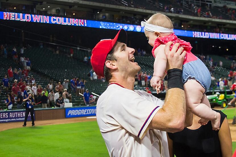 Texas Rangers outfielder Jared Hoying lifts his 6-month-old daughter Carly as he celebrates...