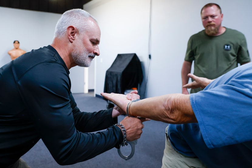 John Dunlap (left) performs a handcuff simulation on Charlie LaShure of Life Fellowship...