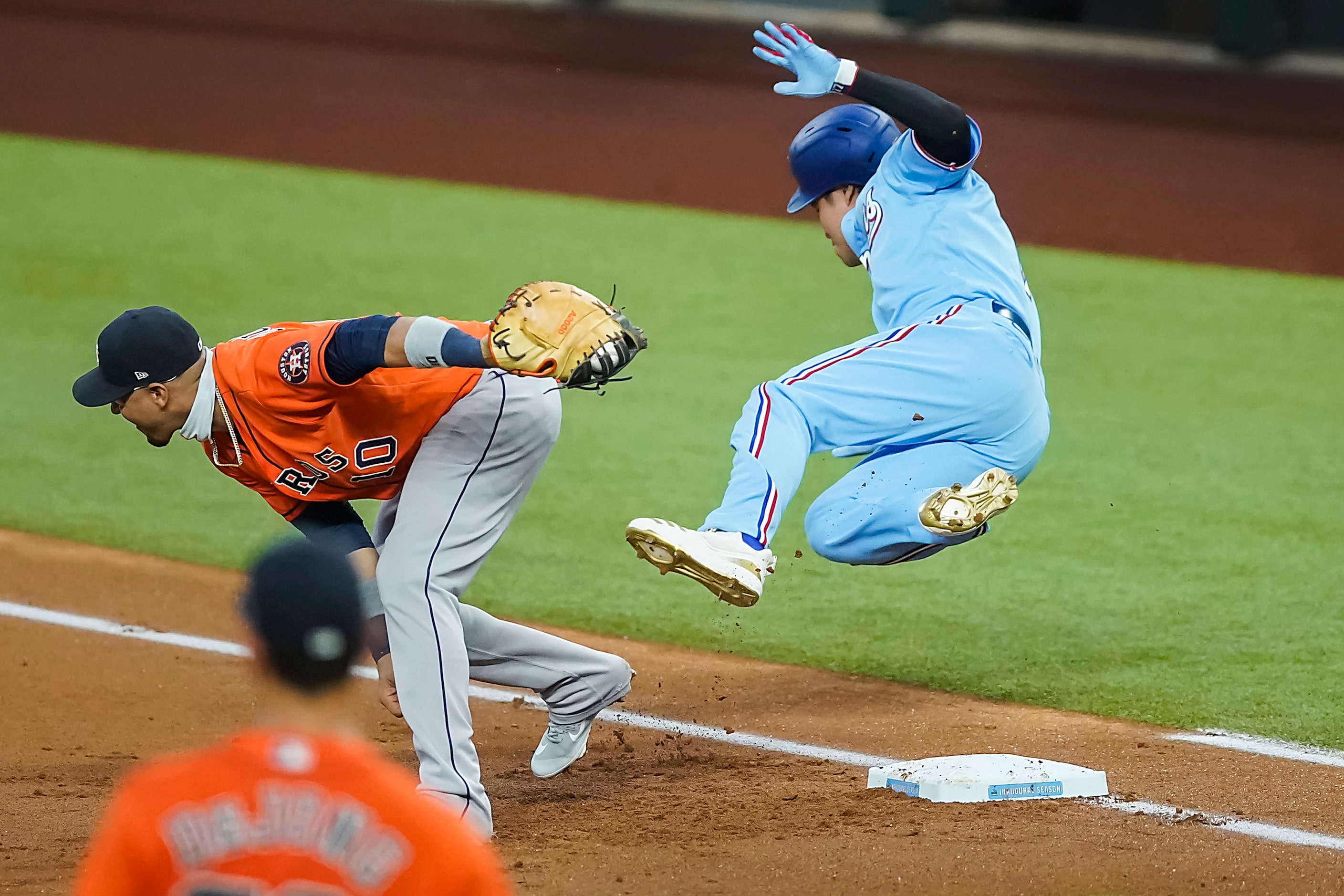 Texas Rangers designated hitter Shin-Soo Choo tumbles over the bag as he beats the throw to...