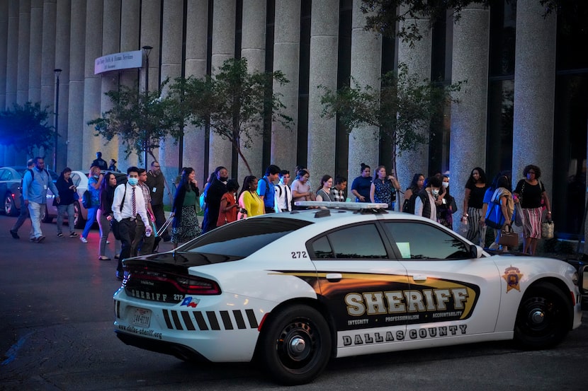 Workers evacuated from the offices of Dallas County Health and Human Services headed toward...