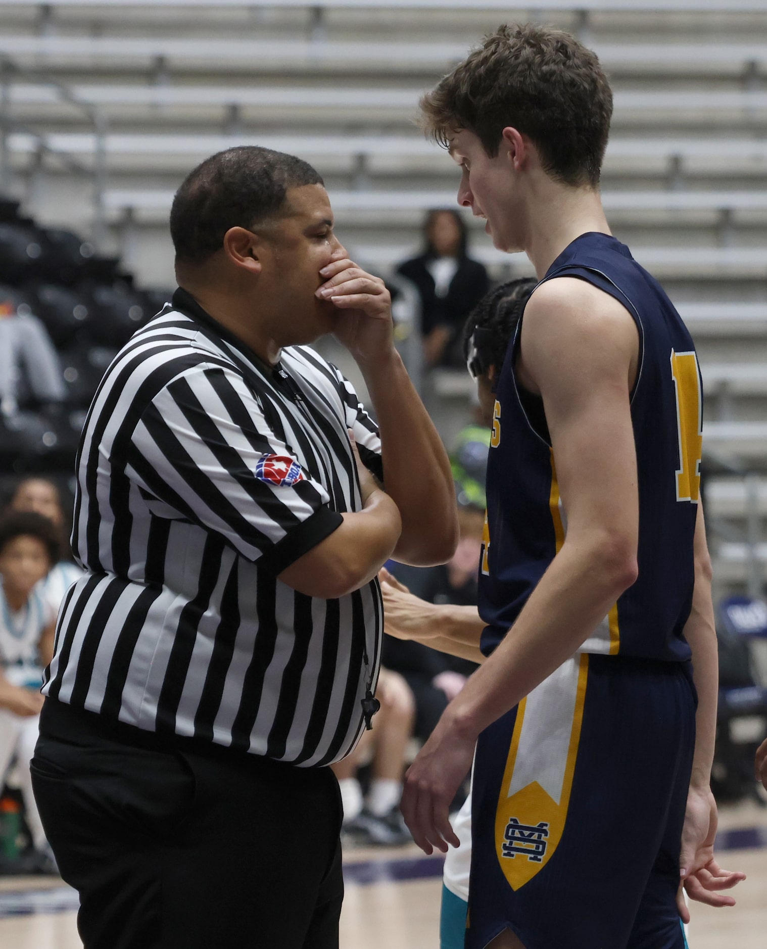 A game official speaks with St. Mark's guard Luke Laczkowski (14), right, during a break in...