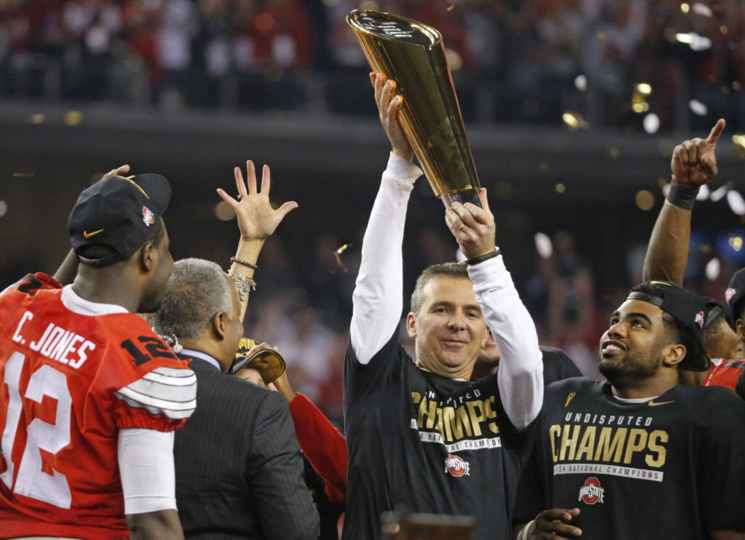 Ohio State head coach Urban Meyer hoists the national championship trophy as running back...