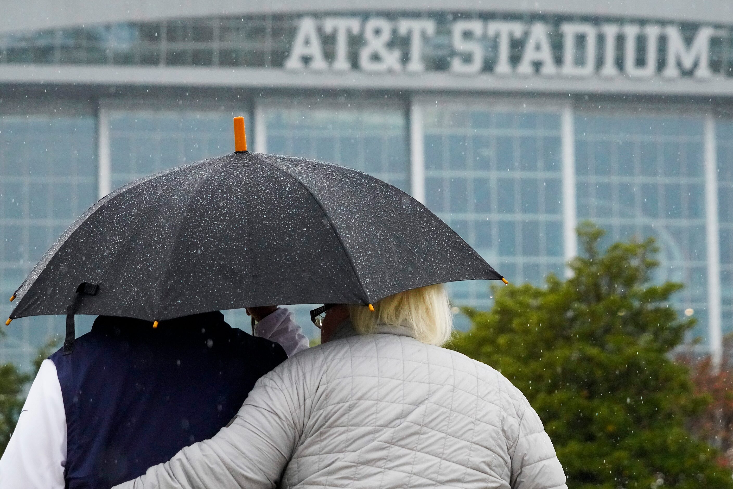 Fans head to the stadium in the rain before an NFL football game between the Dallas Cowboys...