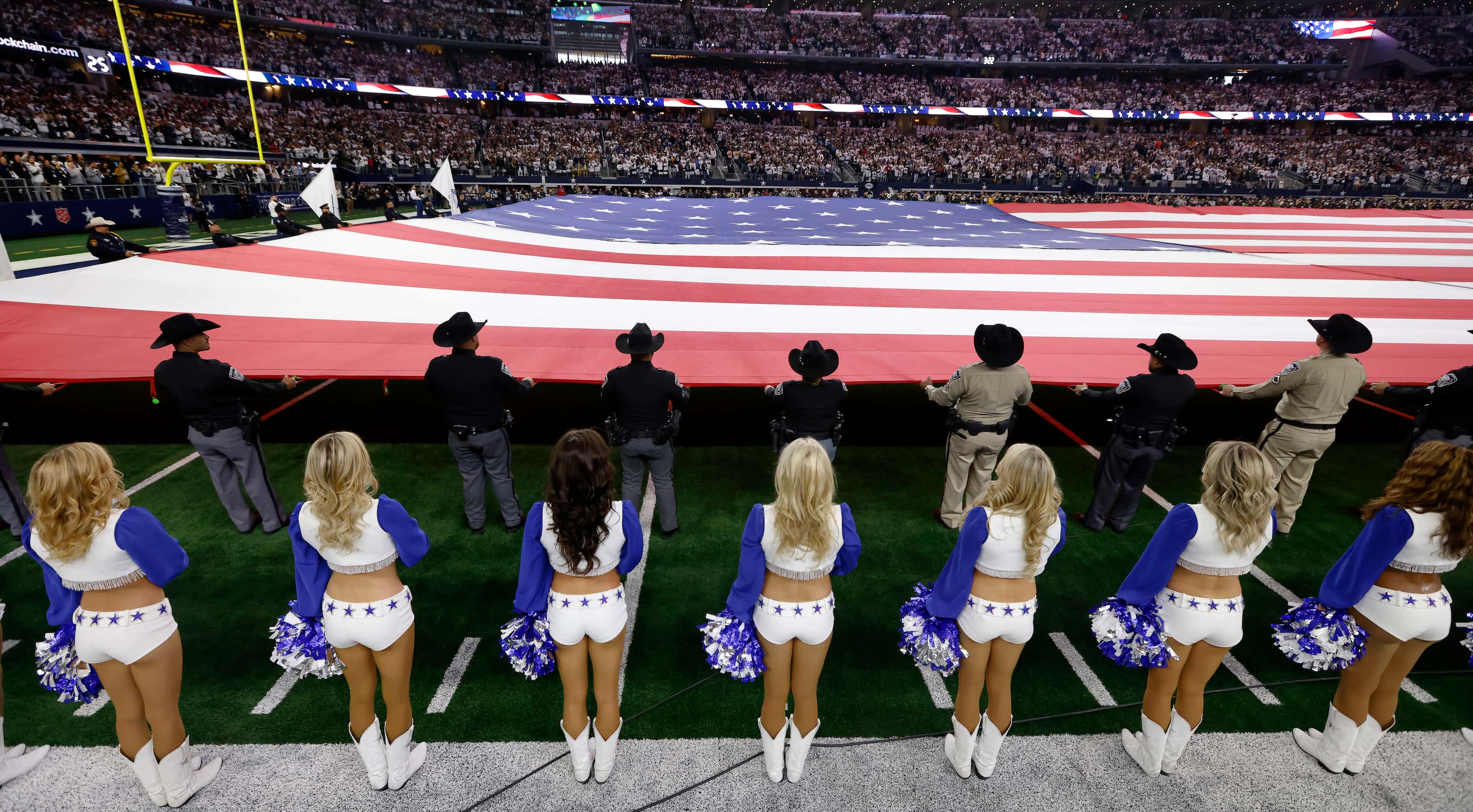 As the Dallas Cowboys Cheerleaders line the sideline, law enforcement officers stretch a...